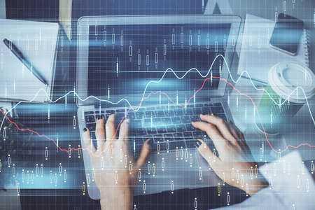 Double exposure of woman hands typing on computer and forex chart hologram drawing. Stock market...