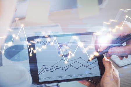 Double exposure of mans hands holding and using a phone and financial chart drawing. Market analysis...