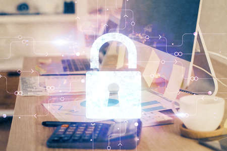 Double exposure of desktop with computer and lock icon hologram. Concept of data safety.