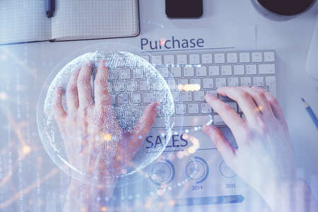 Multi exposure of mans hands typing over computer keyboard and world map hologram drawing. Top view. Technology concept.の写真素材