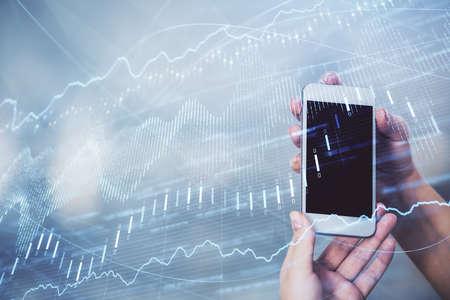 Double exposure of forex graph sketch hologram and woman holding and using a mobile device. Stock...