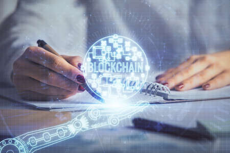 Cryptocurrency hologram over womans hands writing background. Concept of blockchain. Double exposureの写真素材