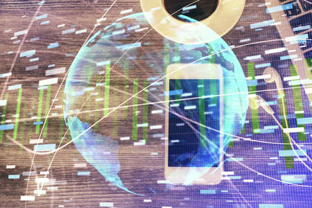 Double exposure of business theme hologram over desktop with phone. Top view. Mobile international...