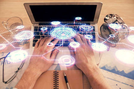 Double exposure of man's hands typing over computer keyboard and social network theme hologram...