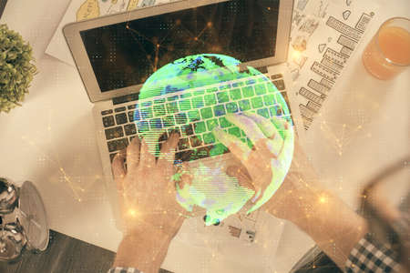 Double exposure of man's hands typing over computer keyboard and social network theme hologram...