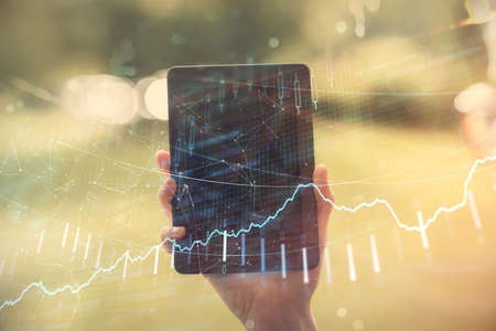 Double exposure of forex chart sketch hologram and woman holding and using a mobile device. Financial market concept.の写真素材