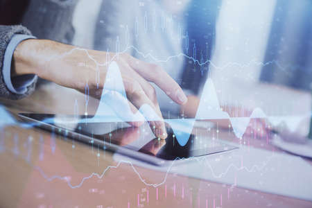 Double exposure of forex graph drawing and man and woman working together holding and using a mobile...