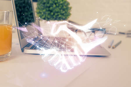 Desktop computer background in office and handshake hologram drawing. Double exposure. Pertnership...