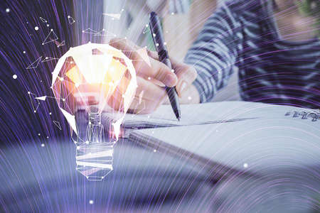 Drawing bulb over woman's hands taking notes background. Concept of idea. Double exposureの写真素材