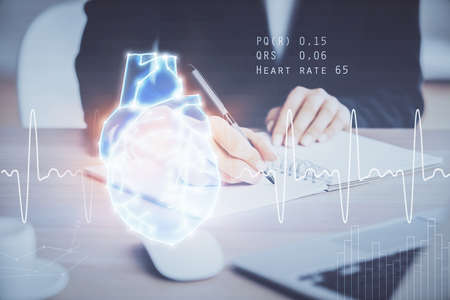 Heart hologram over womans hands writing background. Concept of Medical study. Multi exposureの写真素材