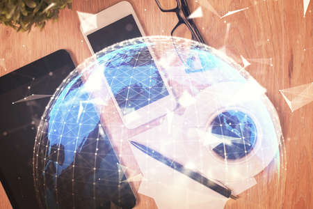 Double exposure of business theme hologram over desktop with phone. Top view. Mobile international trade connection concept.の写真素材