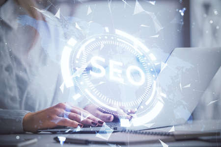 Double exposure of woman hands working on computer and seo hologram drawing. internet search concept.の写真素材