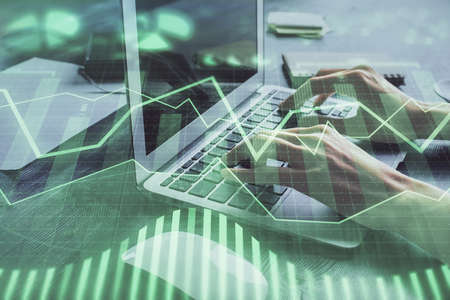 Double exposure of woman hands typing on computer and forex chart hologram drawing. Stock market...