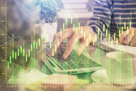 Double exposure of woman hands typing on computer and forex chart hologram drawing. Stock market...