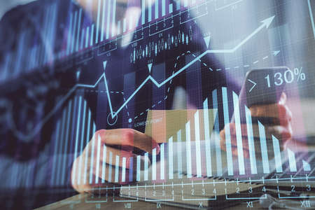 Double exposure of mans hands holding and using a phone and financial graph drawing. Analysis...