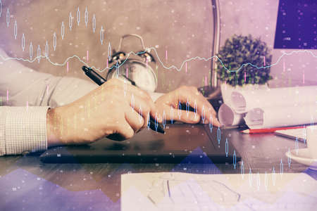 Double exposure of mans hands holding and using a phone and financial graph drawing. Analysis...