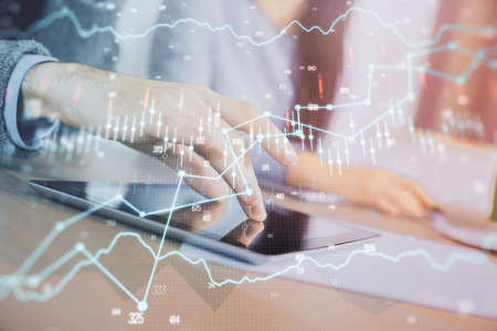 Double exposure of forex graph drawing and man and woman working together holding and using a mobile...