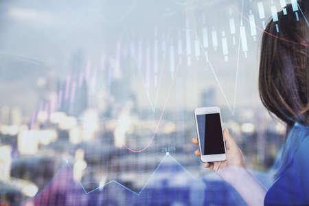 Double exposure of forex chart sketch hologram and woman holding and using a mobile device. Stock...