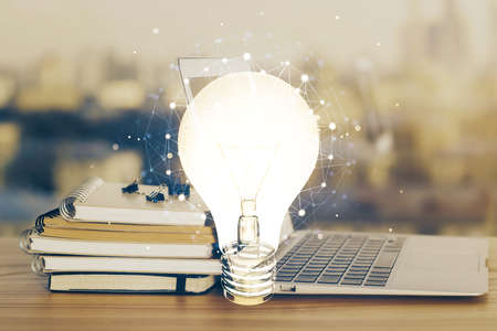 Computer on desktop in office with bulb icon hologram. Multi exposure. Concept of idea.の写真素材