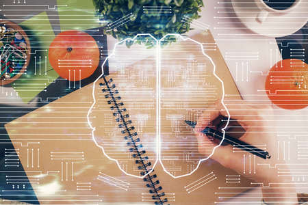 Double exposure of writing hand on background with brain hologram. Concept of learning.