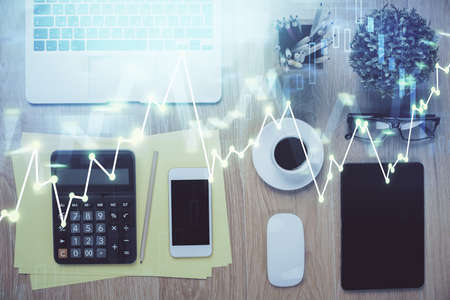 Double exposure of forex chart hologram over desktop with phone. Top view. Mobile trade platform...