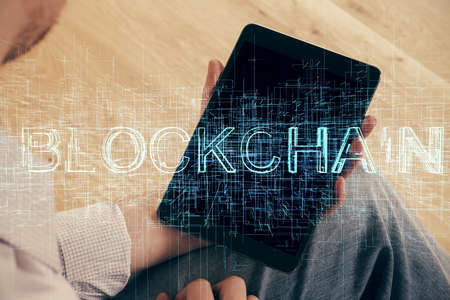 Double exposure of mans hands holding and using a phone and crypto currency block chain theme...