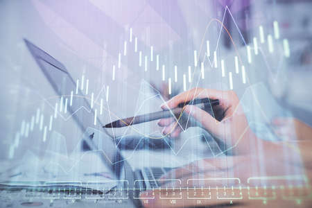 Multi exposure of woman hands typing on computer and financial graph hologram drawing. Stock market...