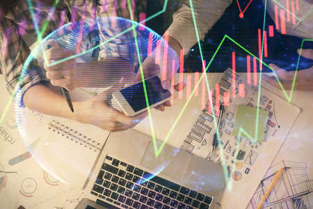 Double exposure of forex graph drawing and man and woman working together holding and using a mobile...