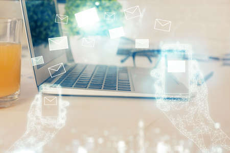 Desktop computer background in office and flying envelops hologram drawing. Multi exposure. Electronic mail concept.の写真素材