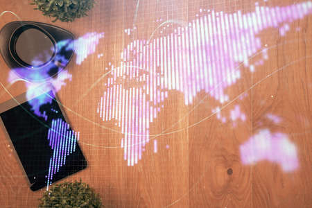 Double exposure of business theme hologram over desktop with phone. Top view. Mobile international...