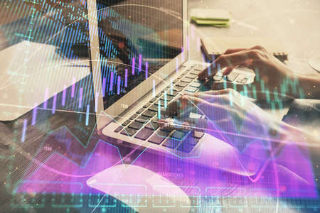 Double exposure of woman hands typing on computer and forex chart hologram drawing. Stock market...