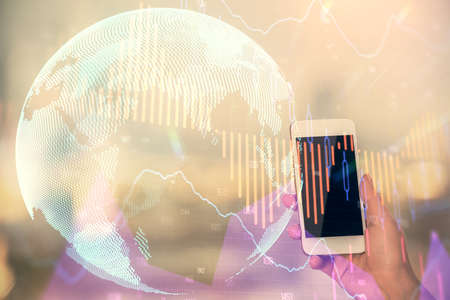Double exposure of forex chart sketch hologram and woman holding and using a mobile device. Stock...
