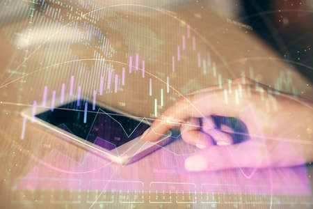 Double exposure of forex chart sketch hologram and woman holding and using a mobile device....