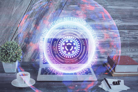 Computer on desktop in office with technology theme hologram. Double exposure. Tech concept.