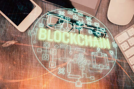 Double exposure of blockchain theme hologram over table with phone. Top view. Crypto technology...