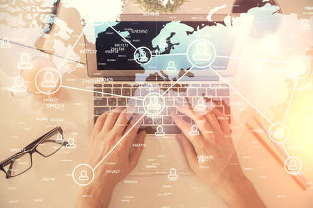 Double exposure of man's hands typing over computer keyboard and social network theme hologram...