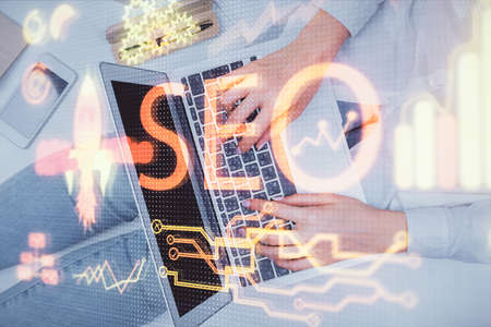 Double exposure of woman hands working on computer and SEO hologram drawing. Top View. Search...