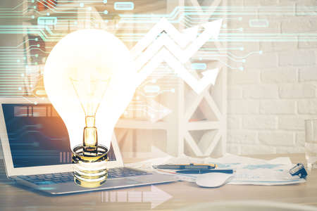 Computer on desktop in office with bulb icon hologram. Multi exposure. Concept of idea.の写真素材