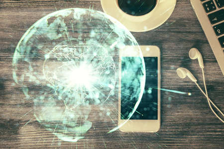Double exposure of business theme hologram over desktop with phone. Top view. Mobile international trade connection concept.の写真素材