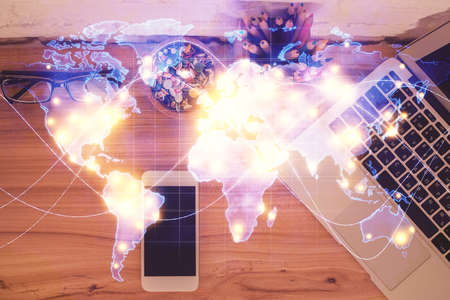 Double exposure of business theme hologram over desktop with phone. Top view. Mobile international...