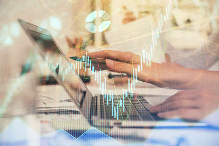 Multi exposure of woman hands typing on computer and financial graph hologram drawing. Stock market...