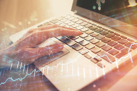 Double exposure of woman hands typing on computer and forex chart hologram drawing. Stock market...