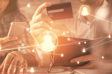 Double exposure of man and woman on-line shopping holding a credit card and social network theme...