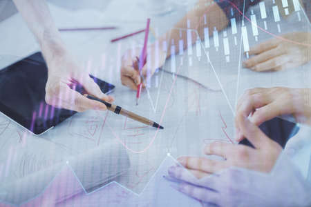 Double exposure of forex graph drawing and man and woman working together holding and using a mobile...