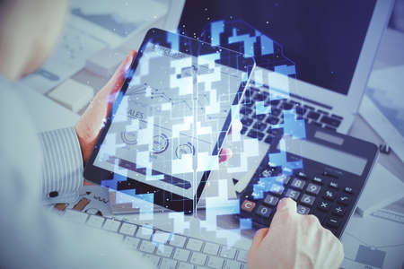 Double exposure of man's hand holding and using a digital device and data theme hologram drawing. Technology concept.の写真素材