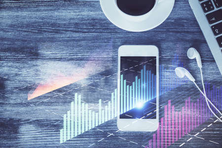 Double exposure of forex chart hologram over desktop with phone. Top view. Mobile trade platform...