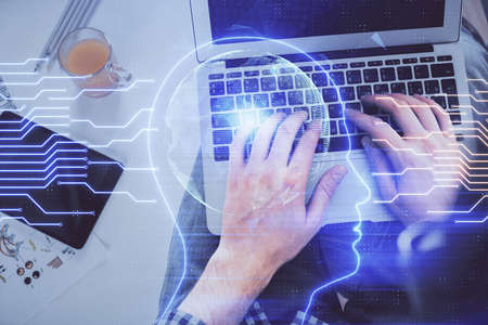 Double exposure of man's hands typing over computer keyboard and brain hologram drawing. Top view....