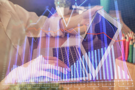 Double exposure of woman hands typing on computer and forex chart hologram drawing. Stock market...