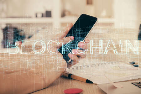 Double exposure of man's hands holding and using a phone and crypto currency blockchain theme...