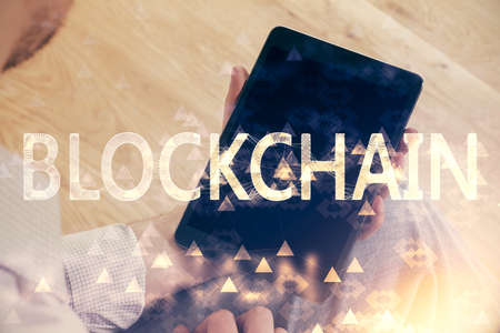 Double exposure of man's hands holding and using a phone and crypto currency block chain theme...